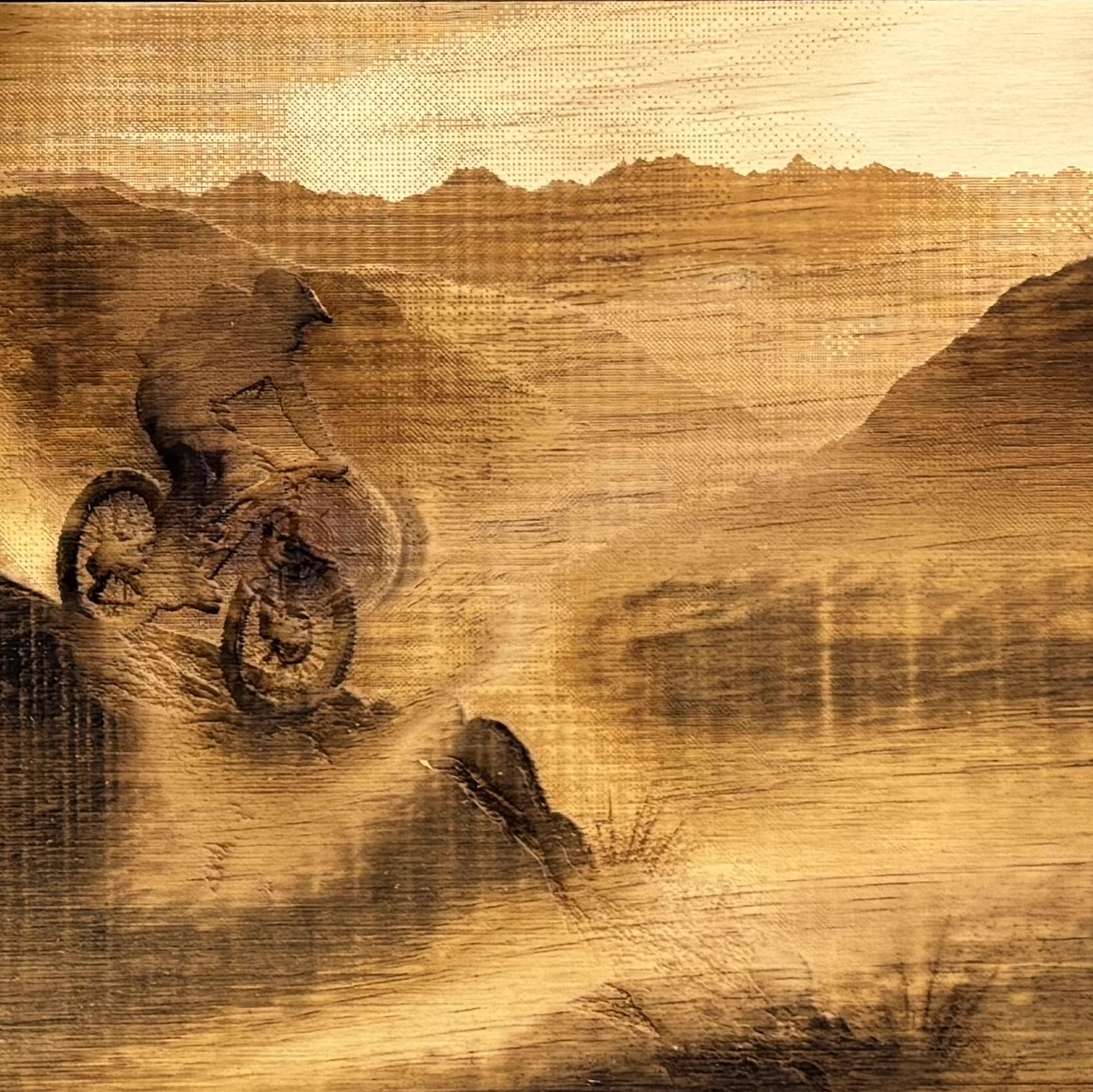 Paysage de montagne et cycliste gravés au laser sur bois