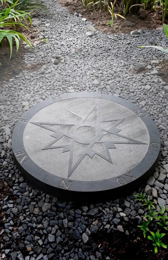 Rose des vents gravée dans un disque de pierre bleue posé au jardin