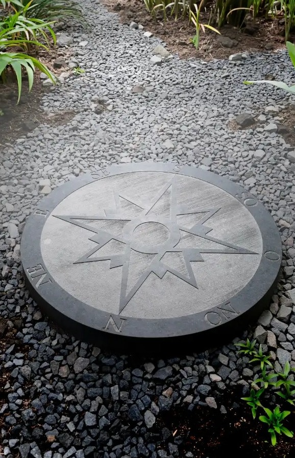 Rose des vents gravée dans un disque de pierre bleue posé au jardin