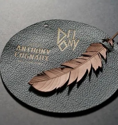 Médaillon de cuir noir gravé du logo Delony avec une plume découpée