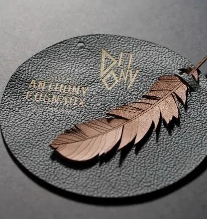 Médaillon de cuir noir gravé du logo Delony avec une plume découpée